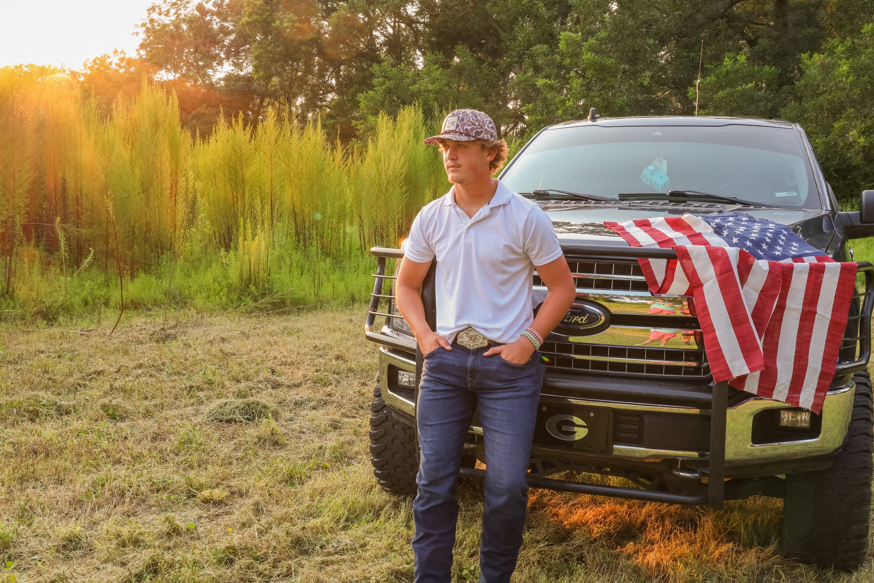 Senior portrait at golden hour beside a truck flying an American flag