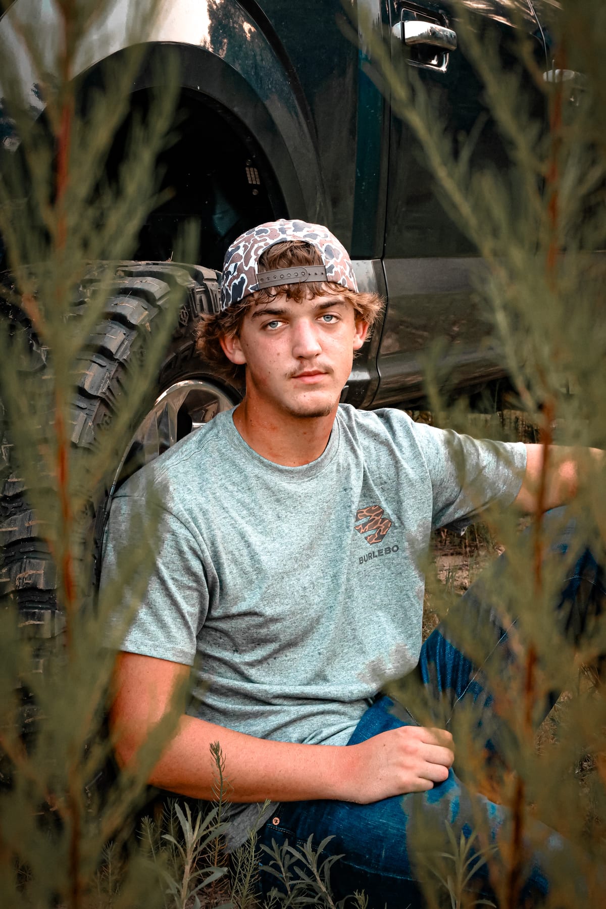 High school senior framed by tall grass at golden hour